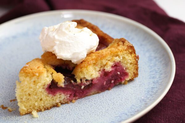 side shot of plum cake with whipped cream.
