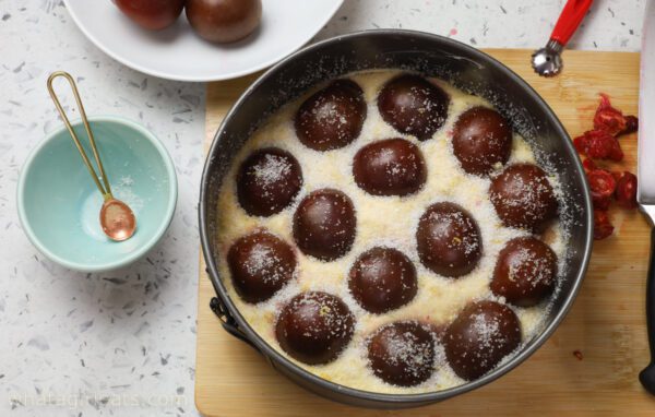 pressing plums into batter sugar on plums.